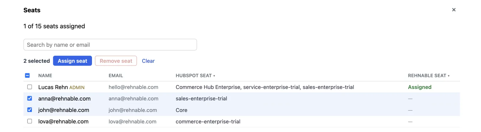 The Seats panel: 1 of 15 seats assigned, a search field, and a table of HubSpot users. Two users are ticked, the toolbar above reads 2 selected with an Assign seat button, and the Rehnable seat column shows Assigned for the admin and a dash for the others.